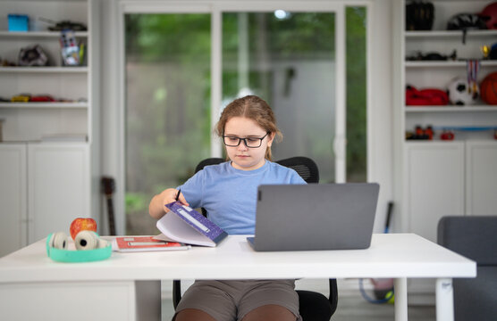 Kid learning at home with laptop and books. Child learn online using laptop at desk. Learning with homework in child room. E-learning on laptop. Kid learning at home. Interior with kid and laptop.