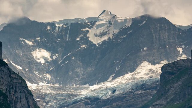 Grindelwald Switzerland alpine mountains timelapse with rushing clouds and moving shadows over majestic snow peaks and lower glacier valley slopes