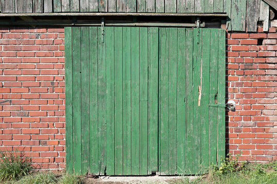 Rustic green barn sliding door on brick wall