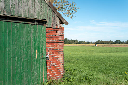 Rural farm shed with tractor cultivating field