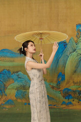 Young Woman in Floral Qipao with Paper Parasol Before Chinese Landscape Painting © TuongThi