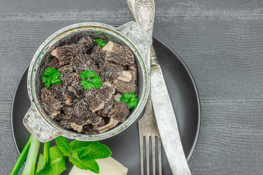 Raw black morel mushrooms with fresh parsley. Vegan ingredient for cooking healthy food