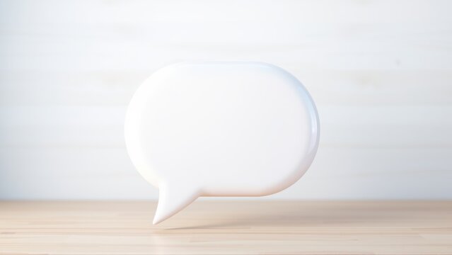 White speech bubble rests upon light wooden surface. Minimalist studio shot, clean aesthetic, simple composition. Focus on communication concept.