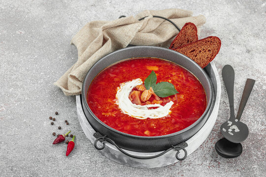 Traditional Ukrainian borscht with sour cream and bay leaves in a bowl, with dark rye bread slices