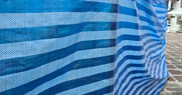 Blue sheets or blue-white woven tarpaulins. Used to cover construction sites. Made from woven PP (polypropylene) or PE (polyethylene) strands. Characterized by being lightweight, tough, and durable.
