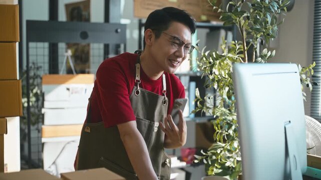 Excited Asian business owner celebrating big order success.