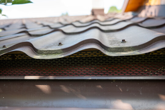 Perforated metal bird guard installed under profiled metal roof tiles, protecting the eaves from birds and small animals while allowing ventilation beneath the roofing.
