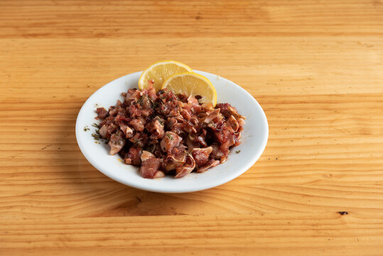 Plate of grilled pig ear with lemon slices.