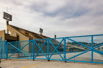 Exterior view of sports stadium stands behind a large blue metal gate in Brazil © Marco Olivetti
