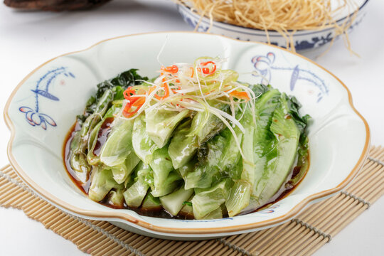 Oyster sauce bok choy on a retro porcelain plate on a sushi mat
