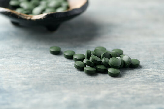 Chlorella tablets. Concept for a healthy dietary supplementation. Rustic wooden background. Soft focus. Copy space.