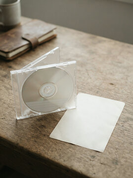 Compact disc in a jewel case beside an envelope on a weathered wood desk
