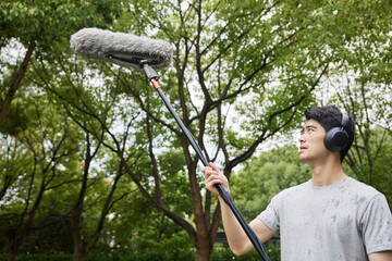 Man Recording Ambient Sound in a Park with Boom Microphone and Headphones © HaXuanDieu