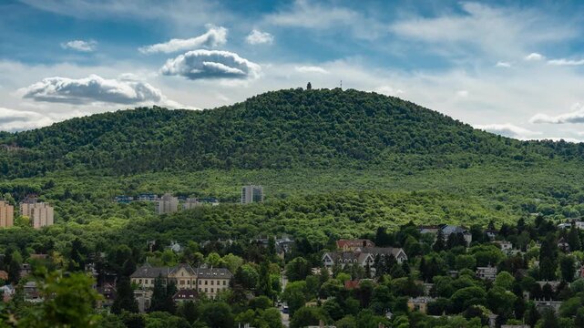 Budapest Janos Hill timelapse with fast rolling clouds over lush green Buda landscape and Elizabeth Lookout Tower under dynamic daylight