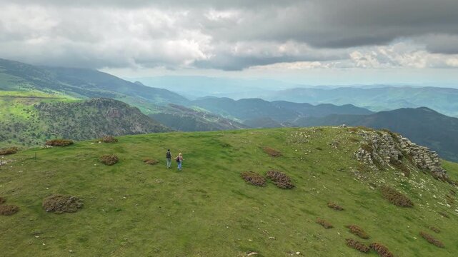 Hikers on a Green Pyrenean Mountain Ridge Beneath Dramatic Clouds