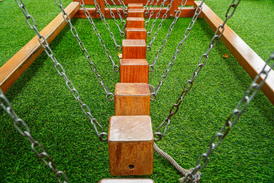 A close-up view of a wooden block chain bridge on artificial grass, ideal for playground or outdoor recreational use, showcasing sturdy construction and vibrant green turf background.