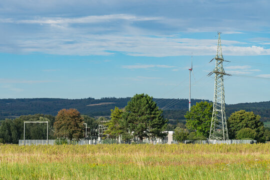 Power lines and structures in a green field landscape