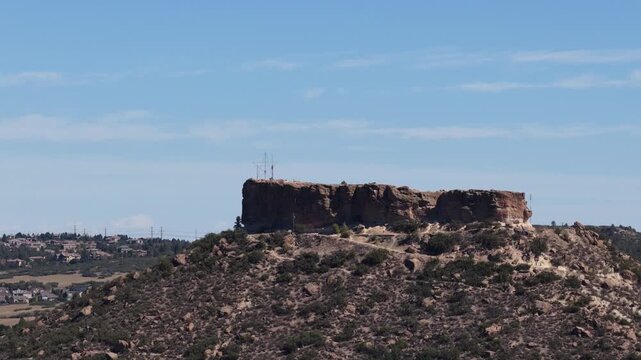 Aerial of Castle Rock formation in Colorado in prominent bluff overlooking homes in summer against blue sky