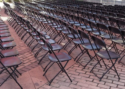 Empty chairs arranged in rows in an outdoor area before an event starts