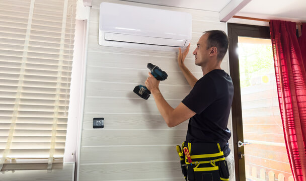 HVAC technician servicing an indoor air conditioner unit mounted on a wall, concept for maintenance service, home repair and technical support 