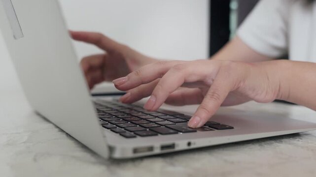 Close-up of hands typing on a laptop keyboard with a blurred background, highlighting focused computer work or digital communication.
