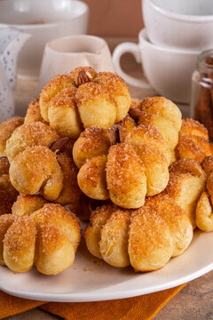 Pumpkin spice buns with almond nuts, cinnamon and sugar crunch. Autumn baking idea, pumpkin puree based vegetable rolls in form of small pumpkins. Tiny sweet pumpkin shaped buns on white plate,