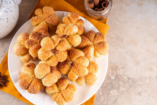 Pumpkin spice buns with almond nuts, cinnamon and sugar crunch. Autumn baking idea, pumpkin puree based vegetable rolls in form of small pumpkins. Tiny sweet pumpkin shaped buns on white plate,