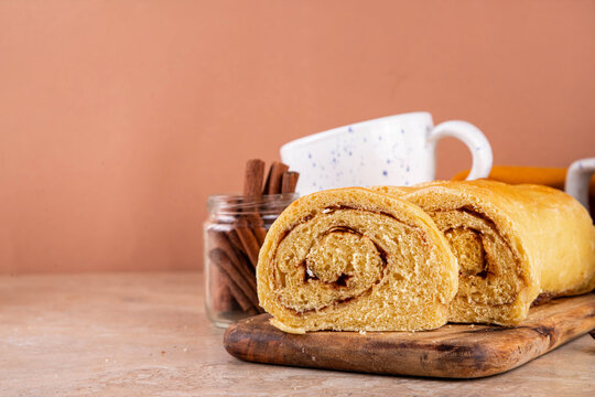 Sourdough Pumpkin Cinnamon Swirl Bread.  Cinnamon roll bread loaf bun with pumpkin puree based dough, tasty sweet cinnamon swirls, on beige background copy space