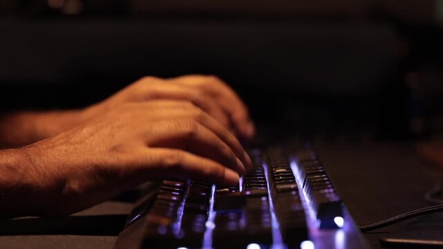 Close-Up of Man Hands Typing on Backlit RGB Mechanical Gaming Keyboard in Dark Office