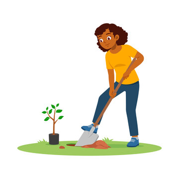 Smiling dark skinned woman digging a hole with a shovel to plant a small tree sapling on green grass