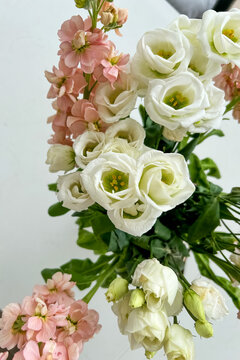 A bouquet of white and pink flowers arranged together against a plain white background