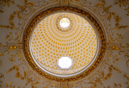 Elaborately decorated domed ceiling with gilded floral ornaments, geometric patterns and skylights inside a historic stately home in North Yorkshire, England.