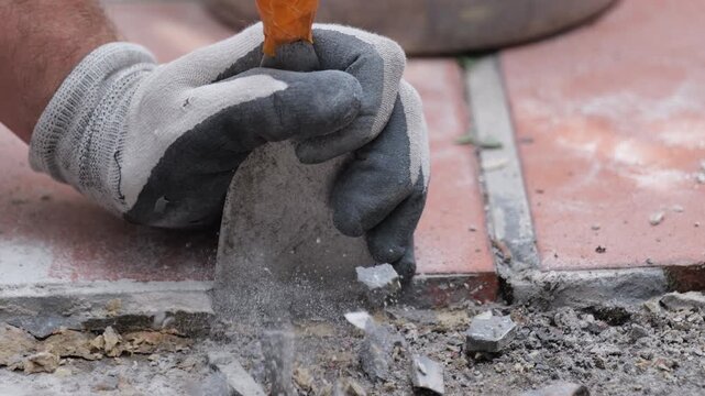 Gloved hand repairing cracked tile floor with putty knife