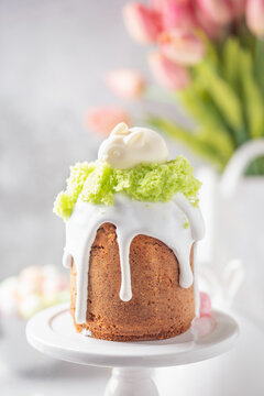 Festive Easter cake decorated with white icing, green flakes, cheesecake bunny and speckled eggs