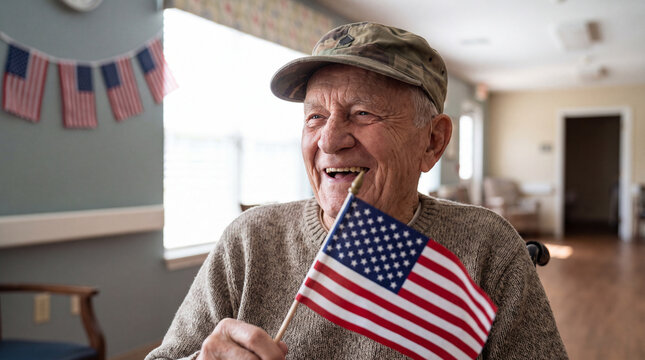 A joyful elderly White male veteran laughs while holding an American flag in a bright nursing home decorated for Veterans Day, ideal for patriotic senior care marketing banners.