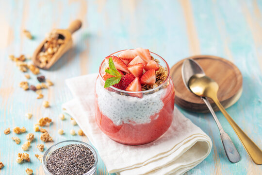 Chia seed pudding with granola, fresh berries and strawberry puree in a glass jar. Healthy breakfast