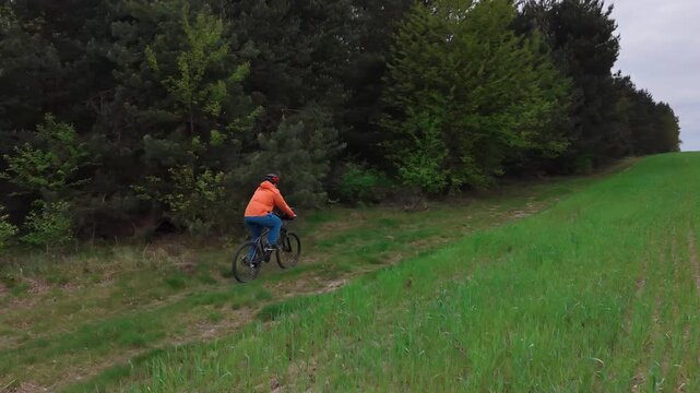Mountain bike rider descending forest trail surrounded by trees