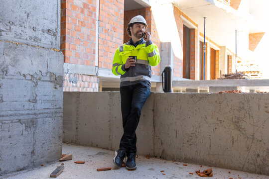 Male engineer talking on smartphone and holding cup