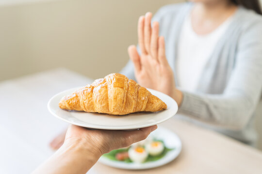 Ketogenic, Low carb, Intermittent Fasting diet woman push out, deny hand push out, deny butter croissant bread on plate, choose green vegetable salad, eat food for good healthy, getting weight loss.