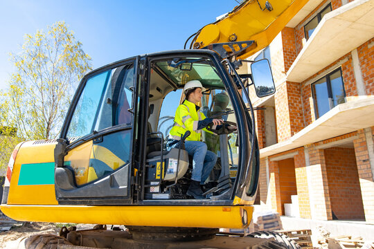 Female heavy equipment operator steering yellow excavator