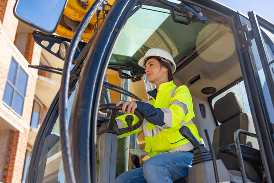 Woman excavator driver looking forward while holding steering wheel
