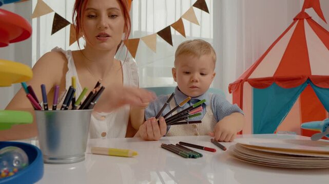 A mother and her young child enjoy a colorful learning session at home, exploring different colors with crayons and creating art together.