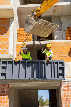 Construction workers installing heavy steel formwork panel