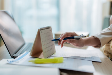 Conceptual image of business time management, professional using a pen to mark dates on a desk...