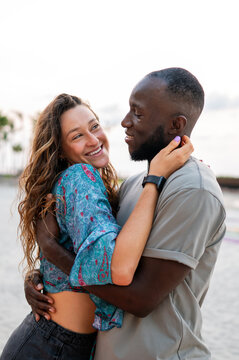 Happy romantic couple kissing on the beach at sunset. Diverse man and woman in love