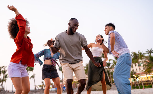 Energetic friends celebrating a summer party on the beach at sunset, embodying the carefree vacation