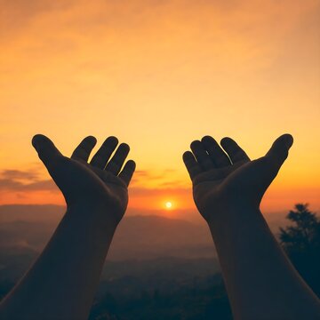 Silhouette of open hands reaching up toward the sky during a warm sunset