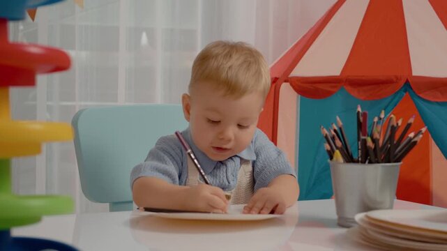 A cheerful boy enjoys drawing with colored pencils at a bright table. Colorful toys surround him while he focuses on his creative artwork.