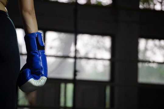 oxing Muay Thai kickboxing glove on woman hand during sport training, close up of hand and wrist strap in gym, showing combat sport equipment, fitness and athletic concept.