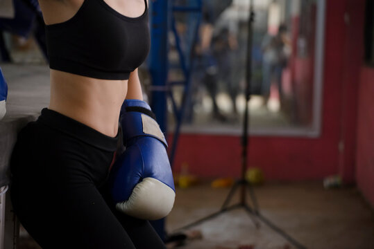 Muay Thai woman and Healthy concept. Boxing Woman prepare to training session and kickboxing, workout at thai boxing gym. Fit Female strap on her wrist and exercise hard to strengthen muscle